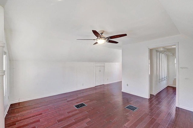 unfurnished room with dark wood-style flooring, visible vents, baseboards, vaulted ceiling, and a ceiling fan