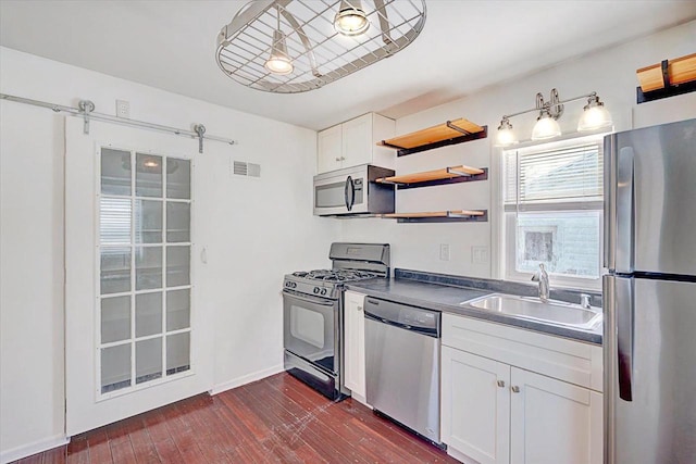 kitchen featuring visible vents, white cabinets, dark countertops, stainless steel appliances, and a sink