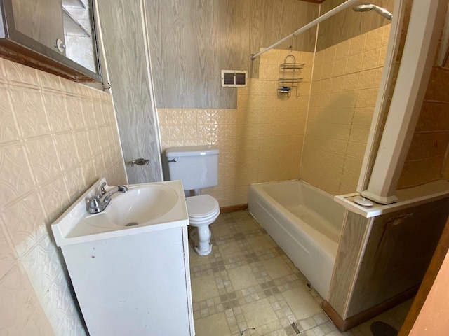 bathroom with shower / tub combination, toilet, visible vents, vanity, and tile walls