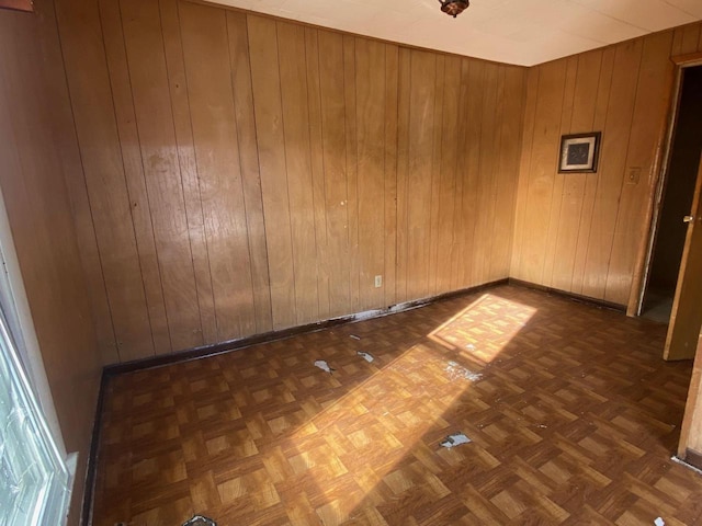 unfurnished room with wooden walls and baseboards