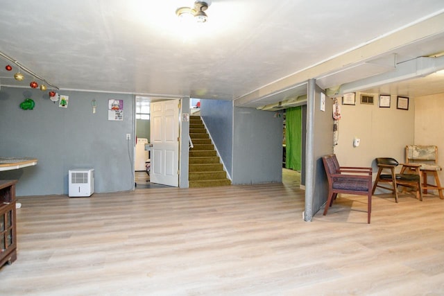 finished basement featuring light wood-style floors and stairway