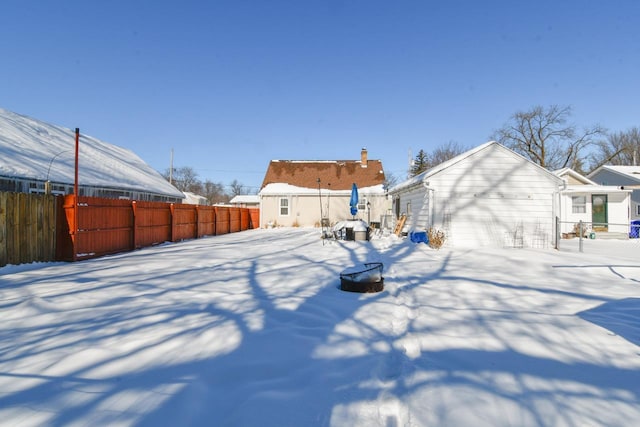 yard covered in snow featuring an outdoor fire pit and fence