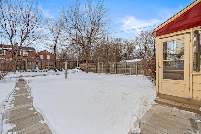 snowy yard with a fenced backyard