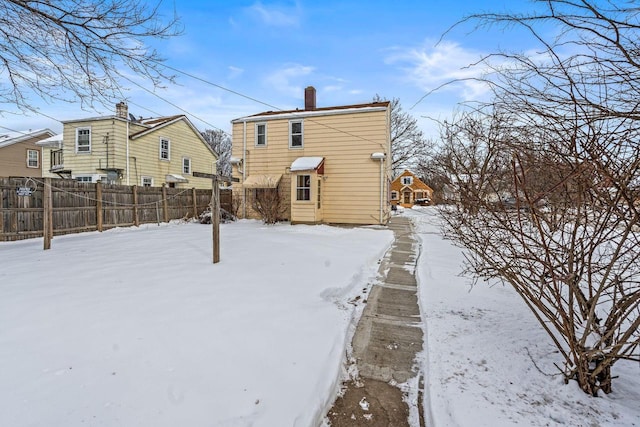 snow covered back of property with fence