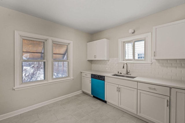 kitchen featuring dishwasher, backsplash, light countertops, white cabinetry, and a sink