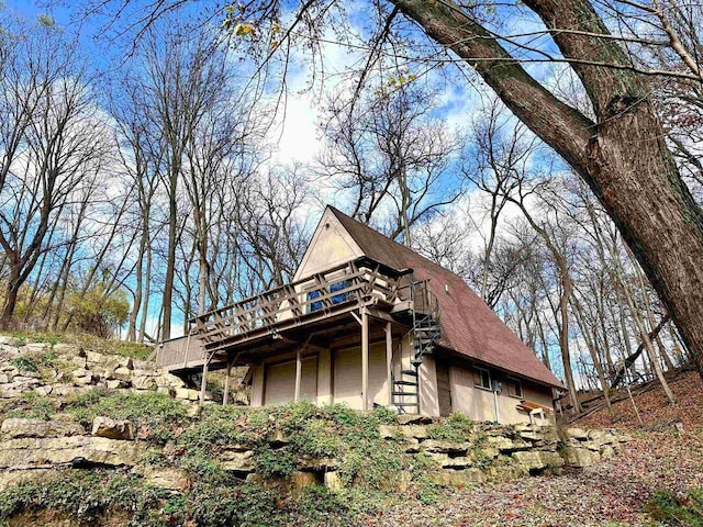 view of side of property with a shingled roof and a deck