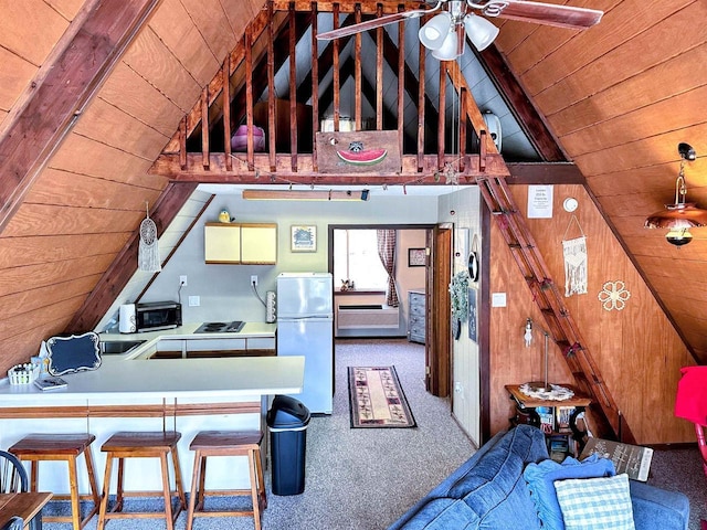 interior space with a breakfast bar area, freestanding refrigerator, carpet flooring, wood walls, and wooden ceiling