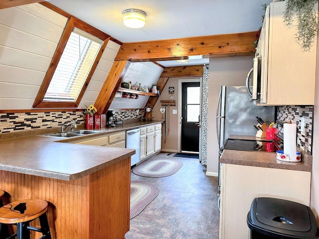 kitchen featuring a peninsula, a breakfast bar, a sink, appliances with stainless steel finishes, and tasteful backsplash