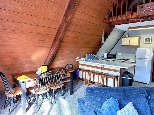 dining area featuring lofted ceiling with beams, wooden ceiling, light speckled floor, and wood walls