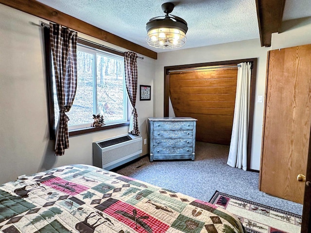 carpeted bedroom with an AC wall unit and a textured ceiling