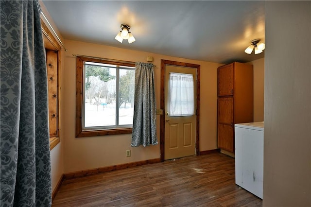 unfurnished dining area with dark wood finished floors, washer / dryer, and baseboards