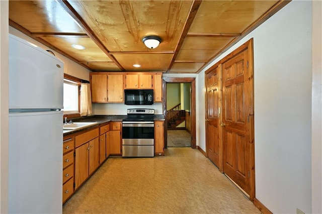 kitchen featuring stainless steel electric range oven, light floors, dark countertops, freestanding refrigerator, and black microwave