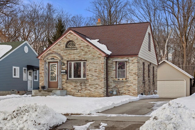 view of front of property with brick siding, a detached garage, a chimney, and roof with shingles