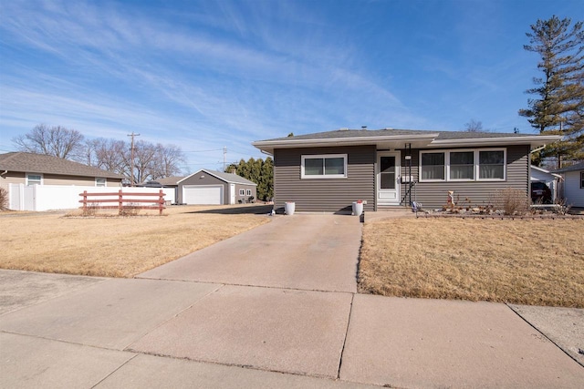 view of front facade featuring an outbuilding, a front yard, fence, a garage, and driveway