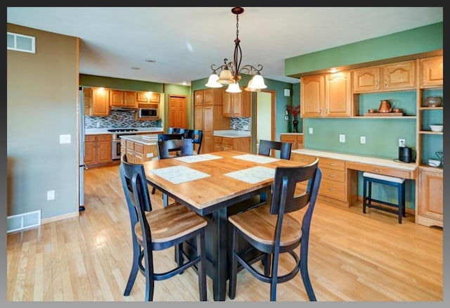 dining area with visible vents, light wood-style flooring, and built in study area