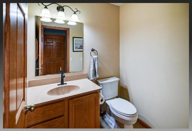 bathroom featuring toilet, vanity, and an inviting chandelier