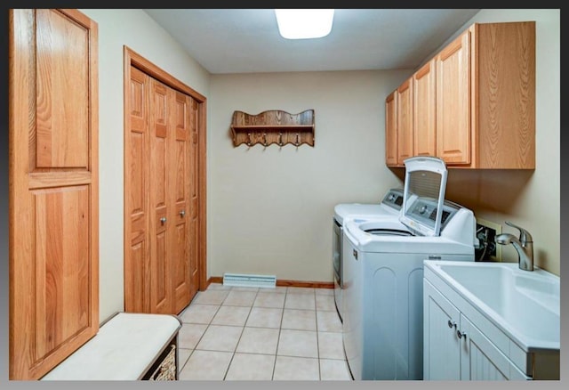 laundry room featuring a sink, cabinet space, separate washer and dryer, light tile patterned floors, and baseboards