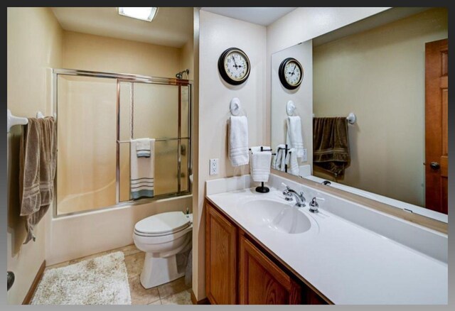 full bathroom featuring shower / bath combination with glass door, toilet, vanity, and tile patterned flooring