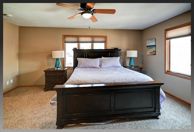 bedroom featuring multiple windows, light colored carpet, baseboards, and a ceiling fan