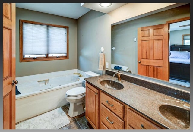 ensuite bathroom featuring toilet, double vanity, a bath, and a sink