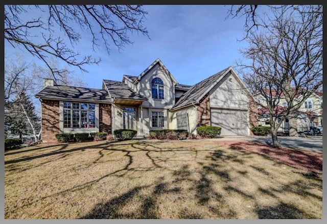 view of front facade with a front yard, driveway, a chimney, a garage, and brick siding