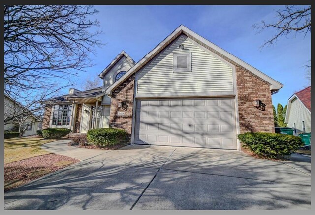 view of front of home with concrete driveway, an attached garage, and brick siding