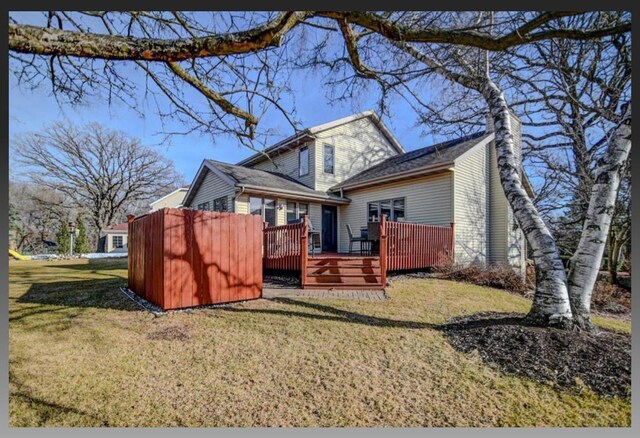 rear view of property featuring a wooden deck, a yard, and a chimney