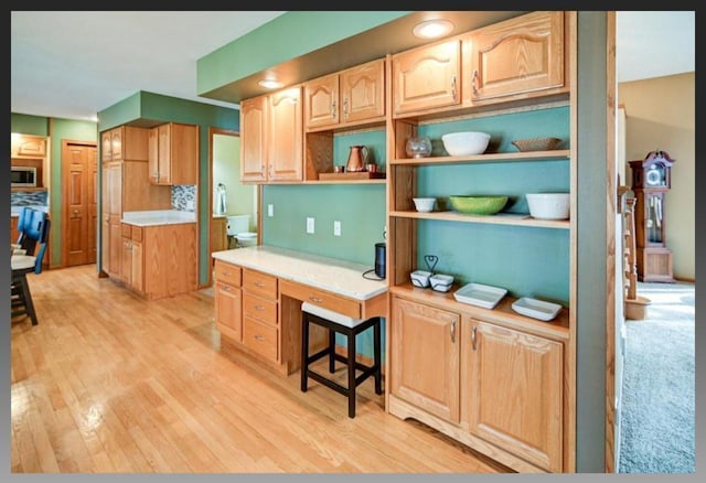 kitchen with stainless steel microwave, light brown cabinets, light wood finished floors, and light countertops