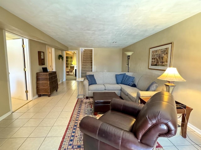 living room featuring stairs, light tile patterned floors, a textured ceiling, and baseboards