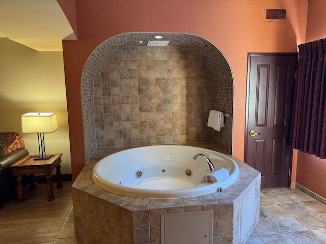 full bathroom featuring a jetted tub, baseboards, and visible vents