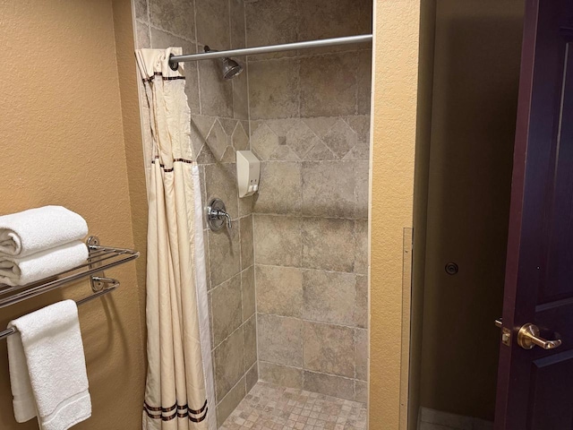 bathroom with a textured wall and a stall shower