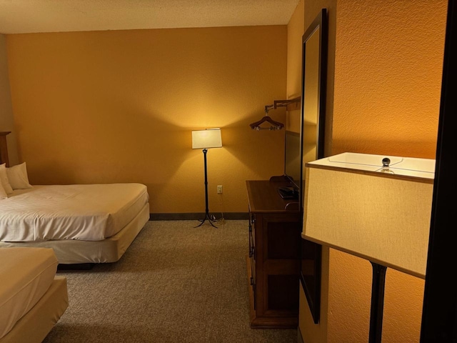 bedroom featuring baseboards and dark carpet