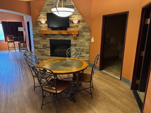 dining area with a stone fireplace, wood finished floors, and baseboards