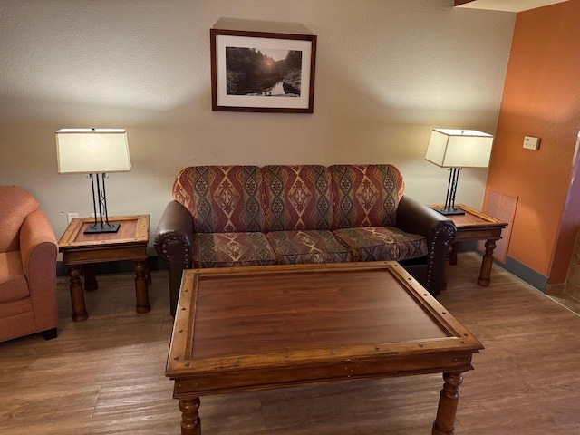 living room featuring wood finished floors, visible vents, and baseboards