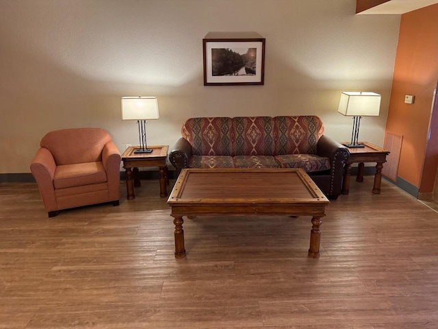 living area with baseboards and wood finished floors