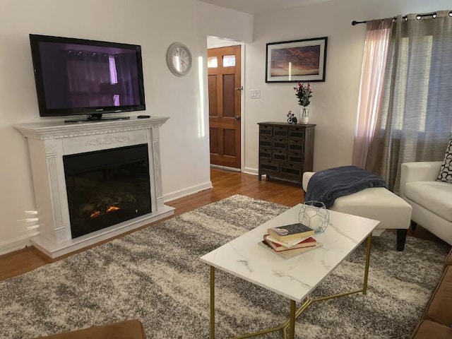 living room with baseboards, dark wood-type flooring, and a glass covered fireplace