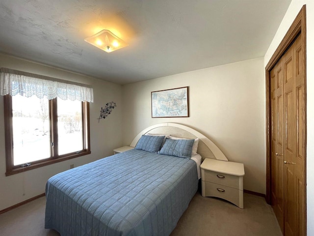 bedroom featuring a closet, light colored carpet, and baseboards