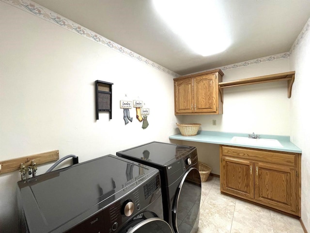 laundry room featuring washing machine and dryer, cabinet space, and a sink