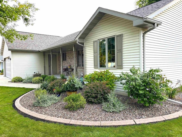 view of side of property featuring a garage, a porch, and roof with shingles