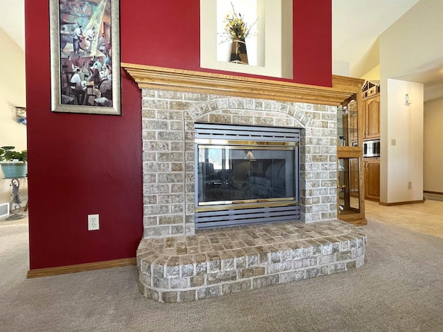 room details featuring stainless steel microwave, carpet, a glass covered fireplace, and baseboards