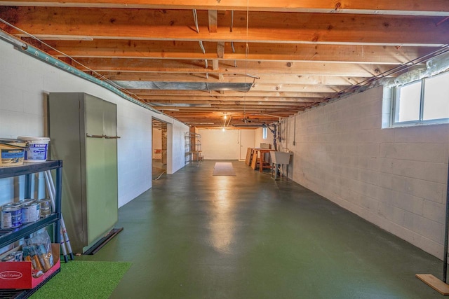 below grade area featuring a sink, freestanding refrigerator, and concrete block wall