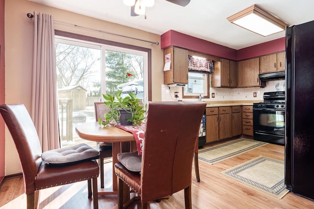 kitchen featuring black appliances, light countertops, a wealth of natural light, and under cabinet range hood