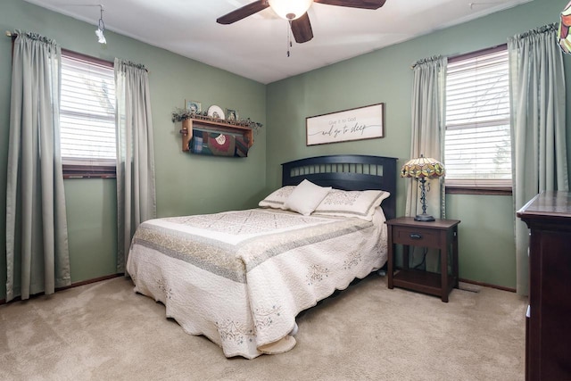 bedroom featuring light carpet, a ceiling fan, and baseboards