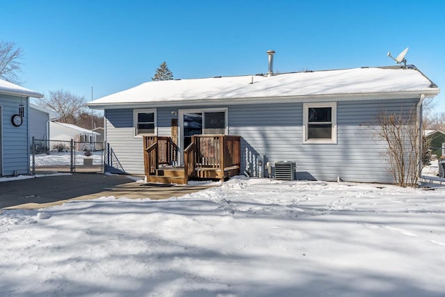 snow covered back of property with central AC and fence