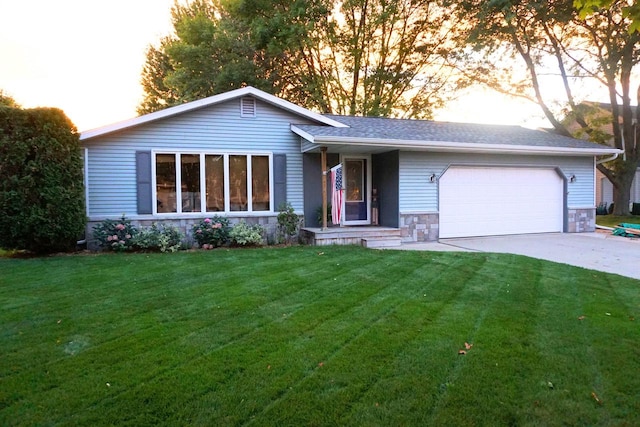 ranch-style home with a yard, a shingled roof, a garage, stone siding, and driveway