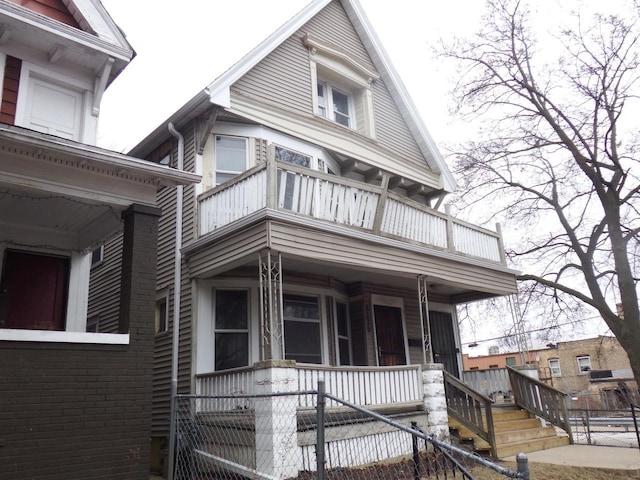 view of front of house with a balcony, a fenced front yard, and brick siding