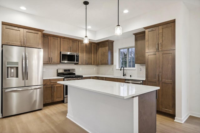 N174W20582 Laurel Springs Cir, Jackson, WI 53037 - kitchen featuring stainless steel appliances, a kitchen island, light countertops, light wood finished floors, and pendant lighting