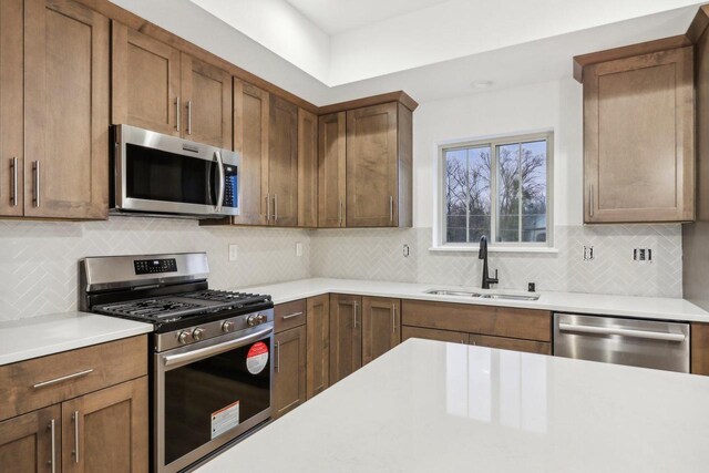 N174W20582 Laurel Springs Cir, Jackson, WI 53037 - kitchen with light countertops, appliances with stainless steel finishes, a sink, and brown cabinets