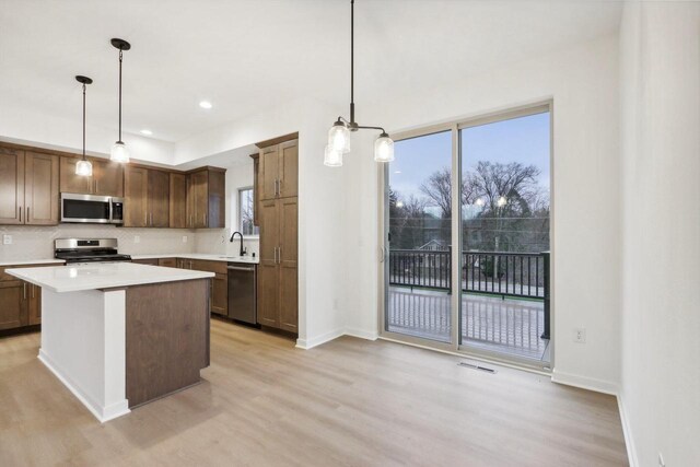 N174W20582 Laurel Springs Cir, Jackson, WI 53037 - kitchen featuring stainless steel appliances, light wood-style floors, light countertops, a center island, and pendant lighting