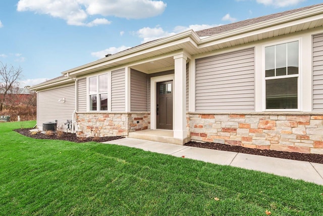 property entrance featuring stone siding, a yard, and central AC unit